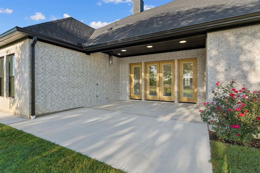 Covered back porch plus huge extended back patio; this space is stubbed out for a range of kitchen configurations! Note the gutters package, the soffit and eaves outlets, and the amazing concrete perimeter.