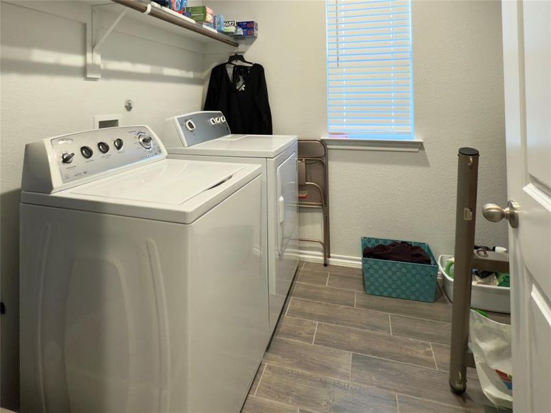 Laundry room with wood finish floors, a textured wall, and washing machine and clothes dryer Laundry room with wood finish floors, a textured wall, and washing machine and clothes dryer