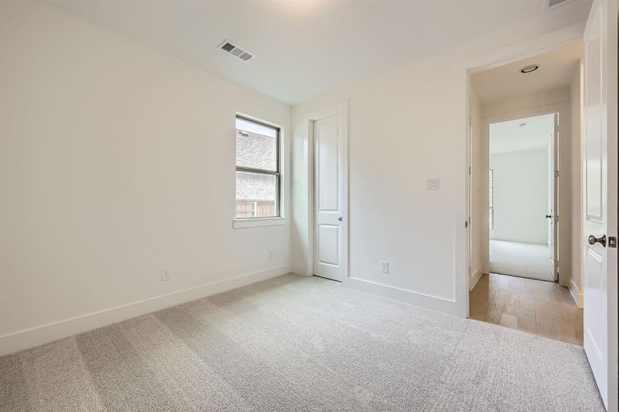Unfurnished bedroom with light colored carpet and baseboards