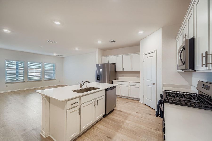 Kitchen featuring stainless steel appliances, open floor plan, light wood-type flooring, white cabinets, and recessed lighting
