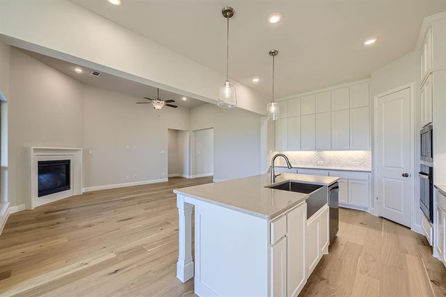 Kitchen with ceiling fan, white cabinets, a center island with sink, and stainless steel appliances