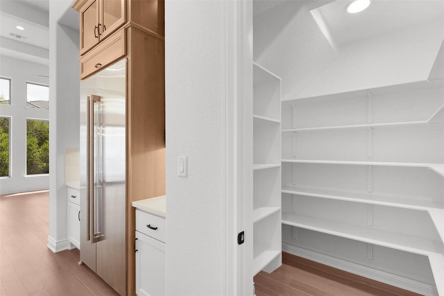 Ample storage solutions define this kitchen, featuring a built-in refrigerator and a spacious walk-in pantry.