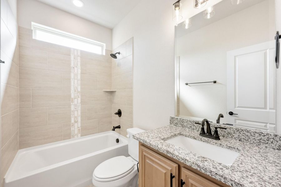 Bathroom with granite countertop vanity, tiled tub-shower combo, and dark bronze fixtures Bathroom with granite countertop vanity, tiled tub-shower combo, and dark bronze fixtures