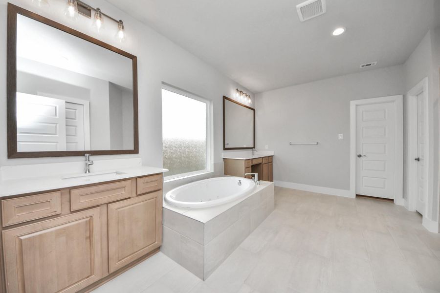 Elevate your daily routine at the elegant vanity, now equipped with double sinks, light countertops, modern hardware, and beautiful vanity lights.