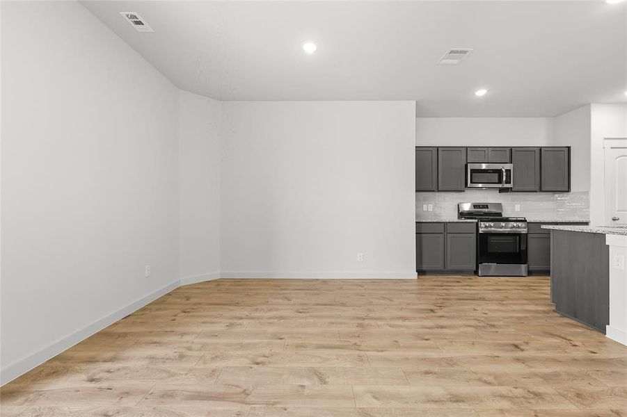 Kitchen with backsplash, stainless steel appliances, light wood-style flooring, gray cabinetry, and recessed lighting