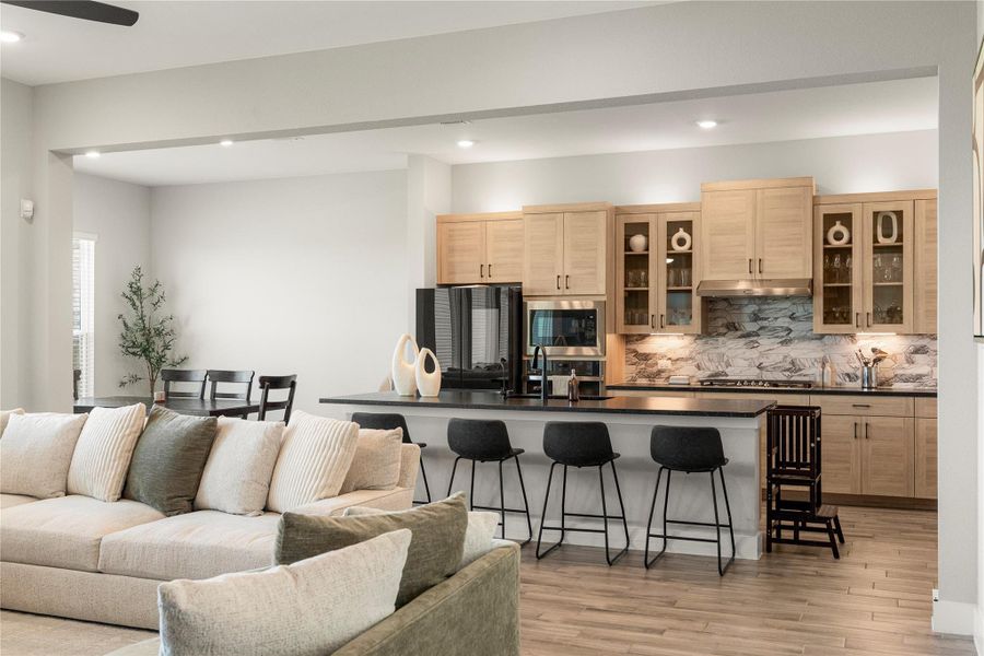 An open-concept living space integrates a well-appointed kitchen with warm wood cabinetry and a chic breakfast bar, featuring contemporary flooring. An open-concept living space integrates a well-appointed kitchen with warm wood cabinetry and a chic breakfast bar, featuring contemporary flooring.
