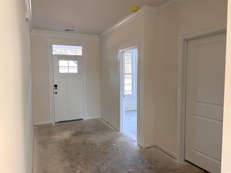 Entryway with concrete floors, plenty of natural light, and crown molding