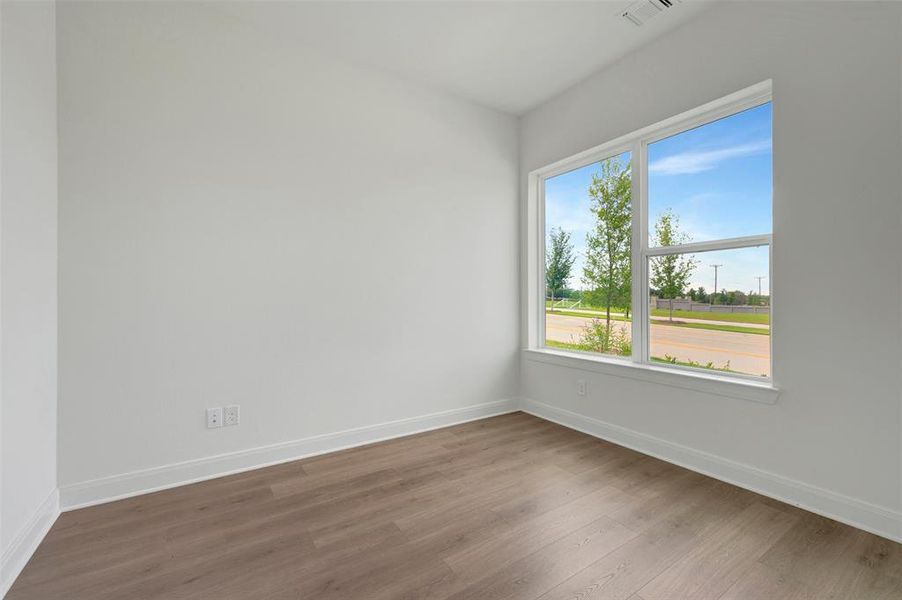 Room featuring a large window, wood-finish flooring, white walls, and white baseboards