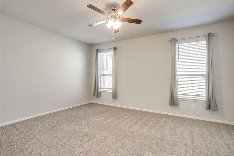 Spare room featuring light colored carpet and a ceiling fan
