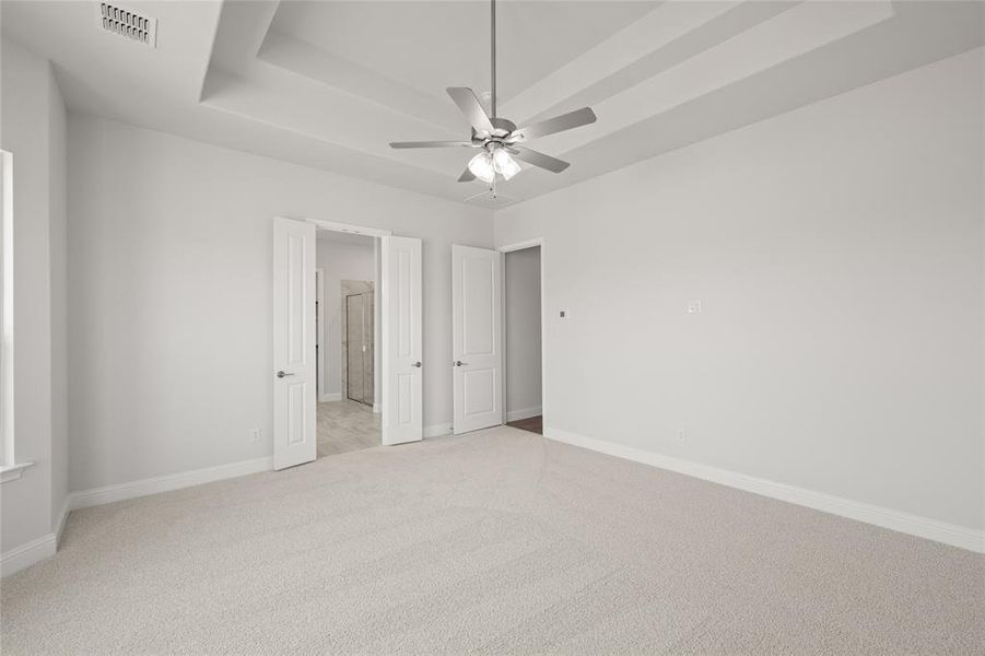 Unfurnished bedroom featuring light colored carpet, baseboards, a tray ceiling, and connected bathroom Unfurnished bedroom featuring light colored carpet, baseboards, a tray ceiling, and connected bathroom