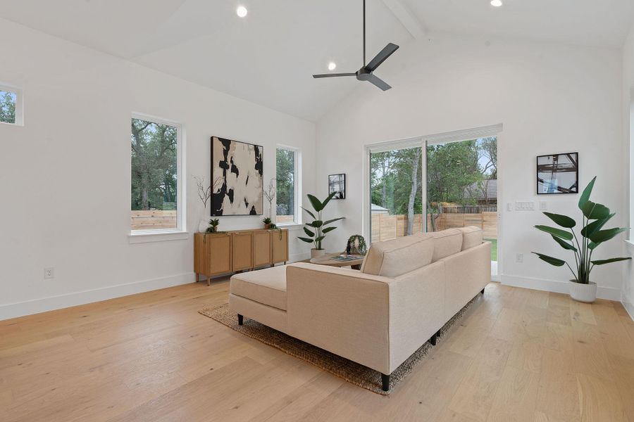 Living room featuring beam ceiling, high vaulted ceiling, light wood-type flooring, recessed lighting, and a ceiling fan Living room featuring beam ceiling, high vaulted ceiling, light wood-type flooring, recessed lighting, and a ceiling fan