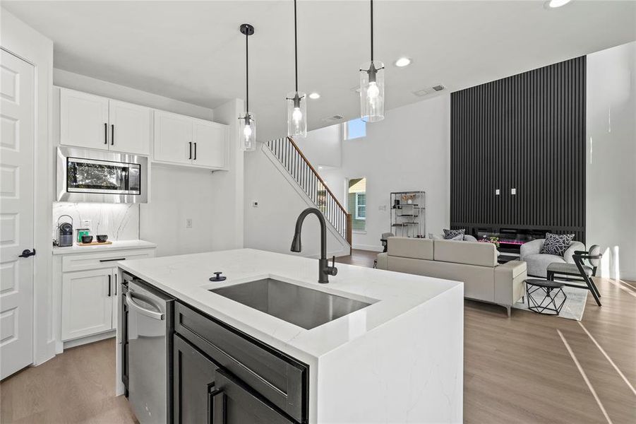 Kitchen featuring sink, white cabinets, hanging light fixtures, and appliances with stainless steel finishes