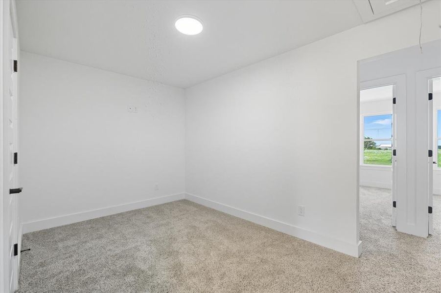 Carpeted empty room with attic access and baseboards