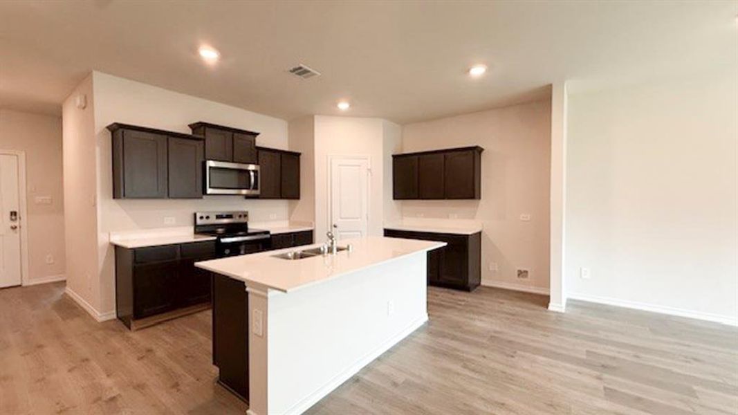 Kitchen featuring stainless steel appliances, light wood-type flooring, an island with sink, and recessed lighting