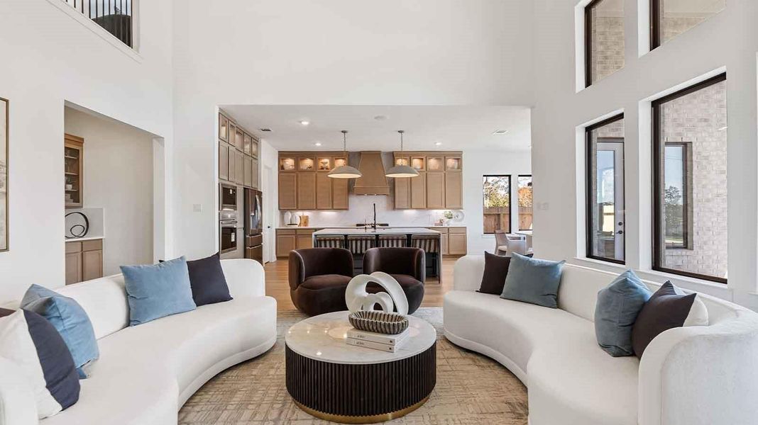 Elegant living room with soaring ceilings, a cozy electric fireplace, open-concept design, and seamless flow into a chef-inspired kitchen.