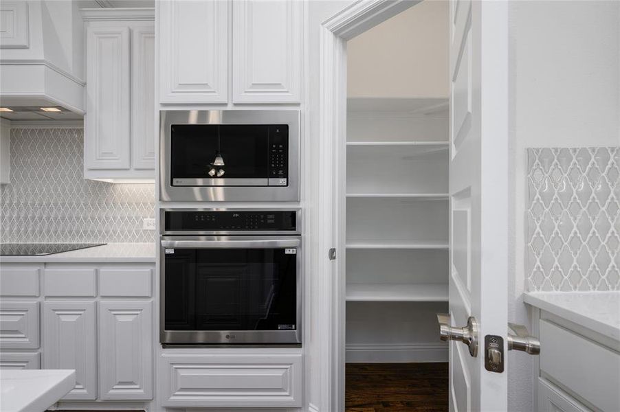 Kitchen featuring premium range hood, tasteful backsplash, white cabinetry, stainless steel appliances, and dark hardwood / wood-style floors