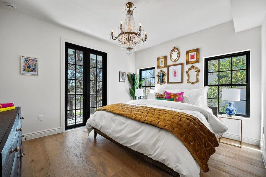 Bedroom with hanging lights, access to outside, and light wood finished floors
