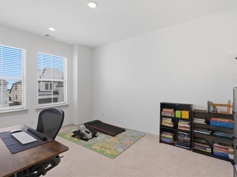 Spacious room featuring two large windows with horizontal blinds, recessed lighting, and neutral-toned carpeting