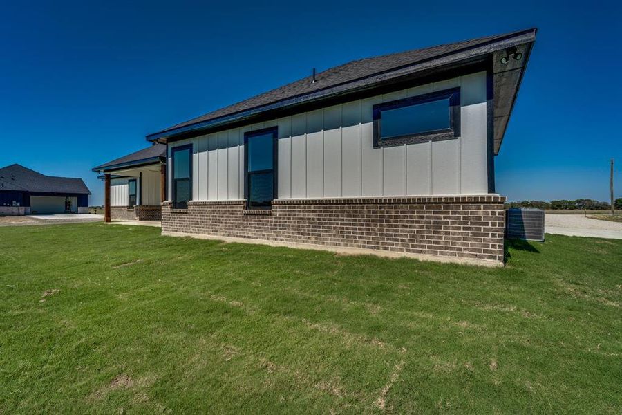 Rear view of property with a garage, a lawn, and central AC