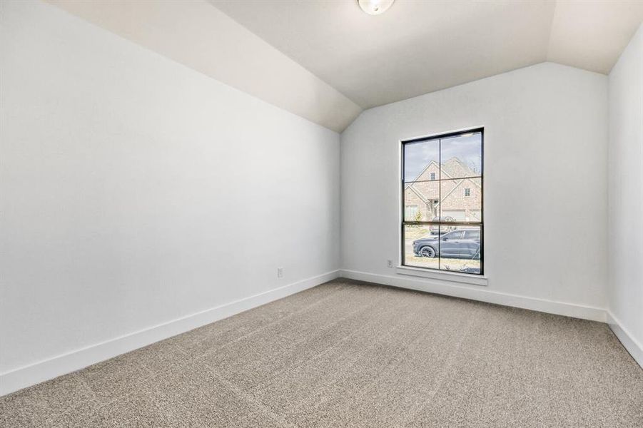 Empty room featuring light carpet and vaulted ceiling