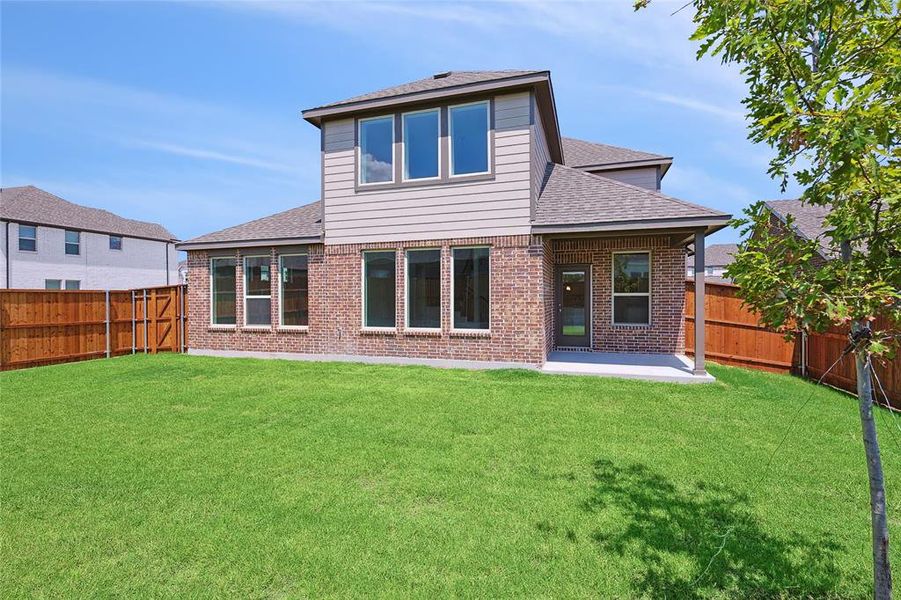 Back of property featuring a lawn and a patio area