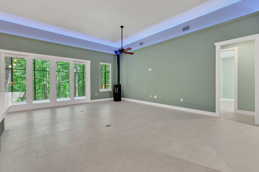 Flow through the front door into the spacious living area with soaring ceilings, ambient lighting, and wall-to-wall windows framing peaceful wooded views.