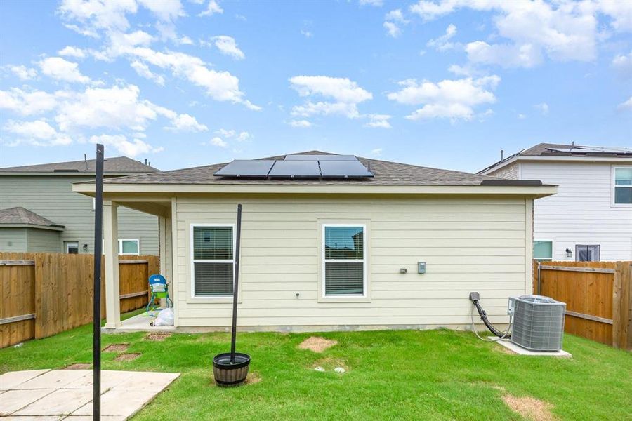 Back of property featuring solar panels, a fenced backyard, a shingled roof, and a patio Back of property featuring solar panels, a fenced backyard, a shingled roof, and a patio