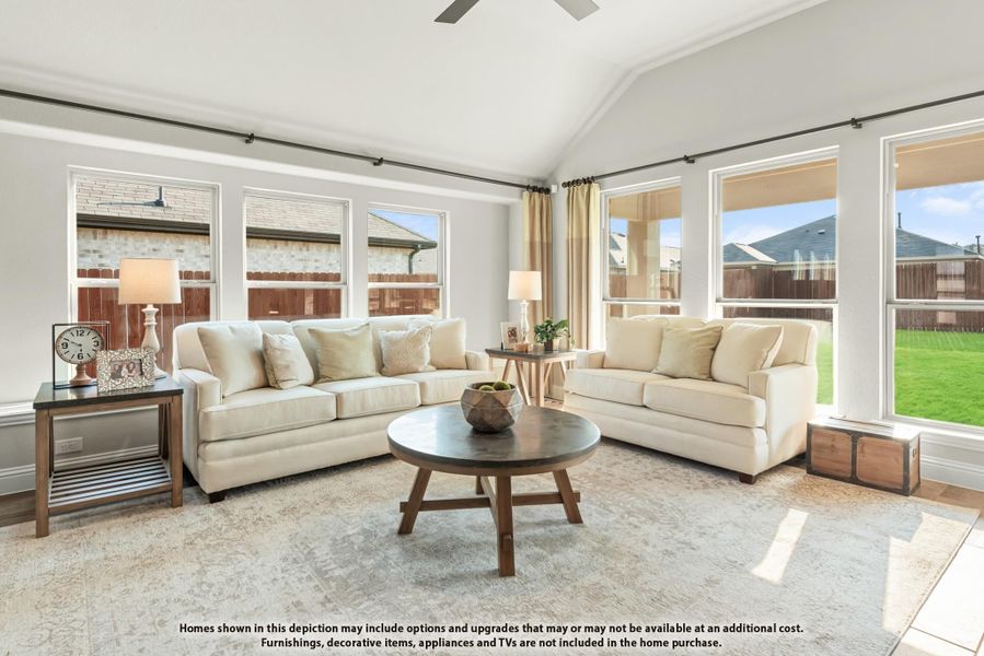 Bright living room with vaulted ceiling, two cream sofas, round wood coffee table, and large windows Bright living room with vaulted ceiling, two cream sofas, round wood coffee table, and large windows
