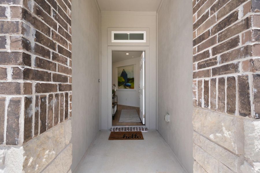 A welcoming front entry, adorned with a transom window and robust brick and stone accents, offers a peek into the home's interior.