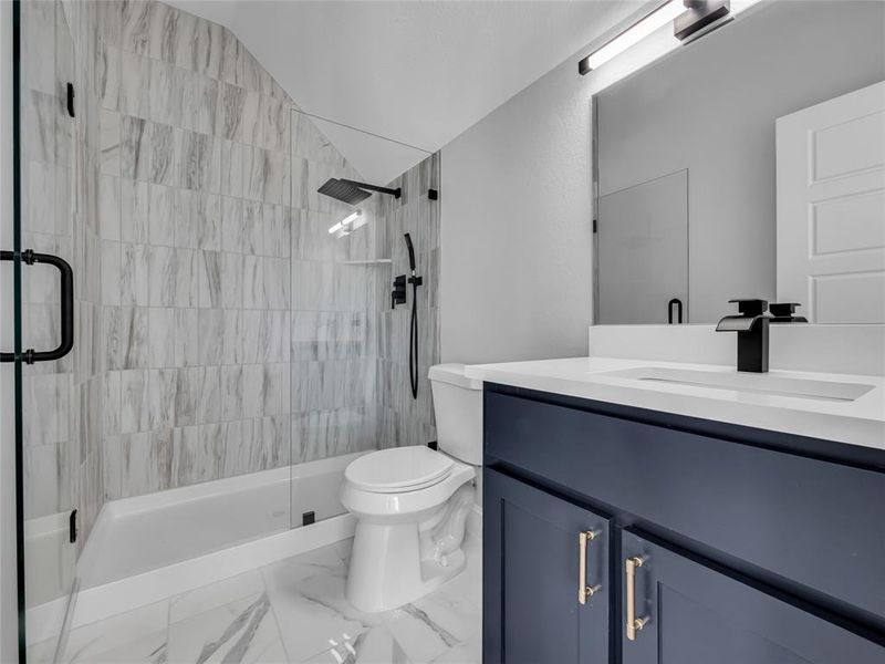 Bathroom with vanity, a shower stall, and marble look tiles Bathroom with vanity, a shower stall, and marble look tiles