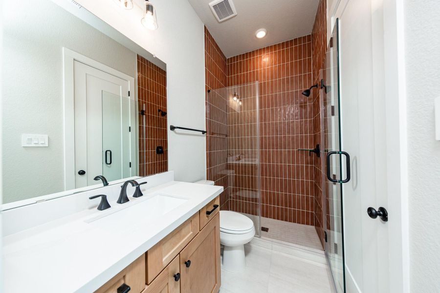 This ensuite secondary bathroom features a modern vanity, large walk-in shower with gorgeous modern tile surround, and modern black matte finishes. This ensuite secondary bathroom features a modern vanity, large walk-in shower with gorgeous modern tile surround, and modern black matte finishes.