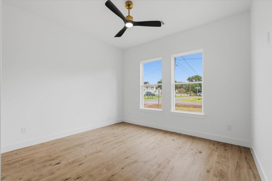 Bright & Versatile. This generous secondary bedroom offers beautiful neighborhood views, warm wood-look flooring, and a stylish black-and-gold ceiling fan—perfect for a guest room, kids' room, or home office!