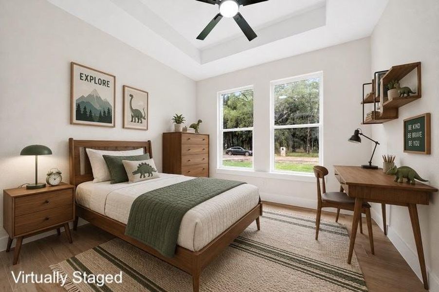 Tray ceiling with a ceiling fan, two large windows, wood-finish flooring, and built-in wall shelving Tray ceiling with a ceiling fan, two large windows, wood-finish flooring, and built-in wall shelving