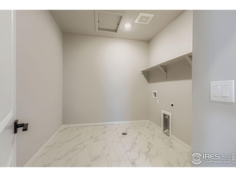 spacious laundry, access from hallway and primary closet, tiled floor