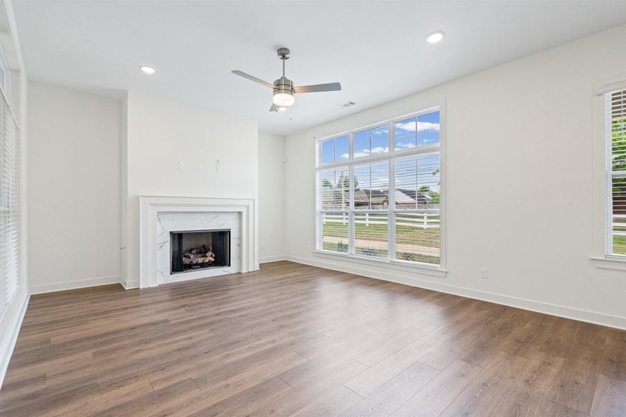 Unfurnished living room featuring ceiling fan, recessed lighting, a high end fireplace, and dark wood-type flooring