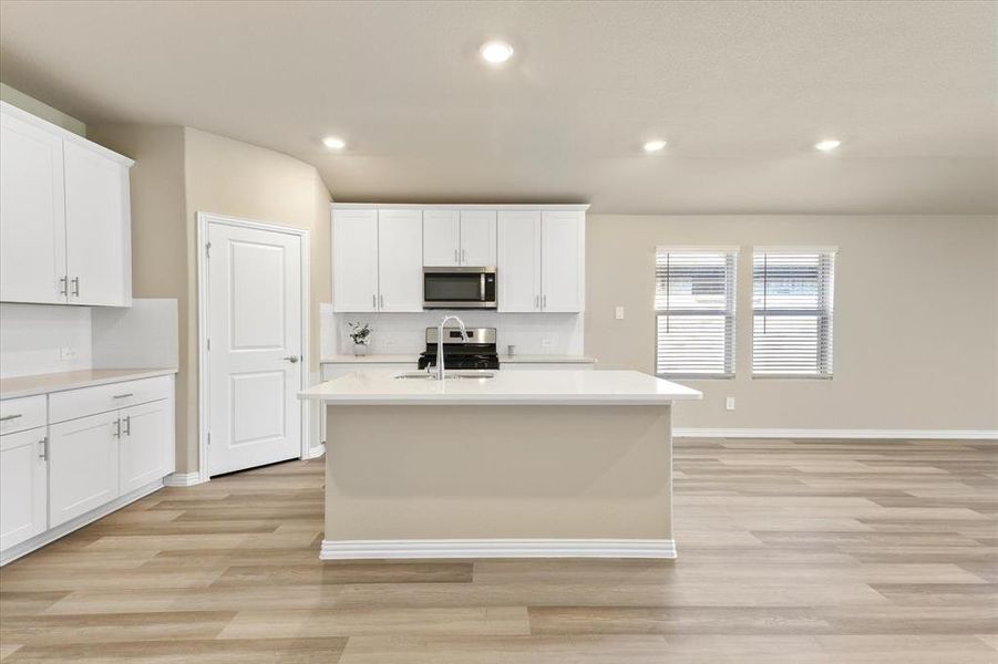 Kitchen featuring white cabinetry, a kitchen island with sink, recessed lighting, tasteful backsplash, and light wood-style floors Kitchen featuring white cabinetry, a kitchen island with sink, recessed lighting, tasteful backsplash, and light wood-style floors
