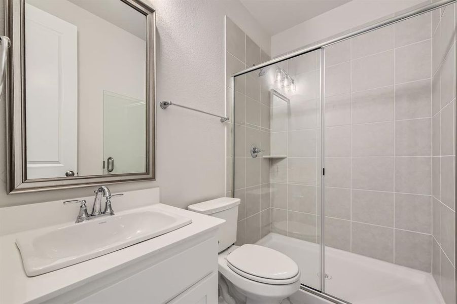 Bathroom featuring vanity, a shower with door, and toilet