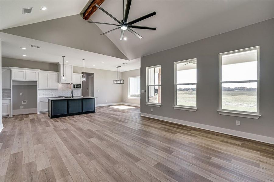 Unfurnished living room with light hardwood / wood-style flooring, beam ceiling, and a healthy amount of sunlight