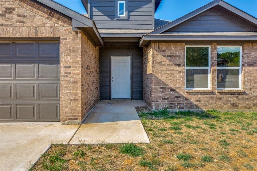 Property entrance featuring brick siding and an attached garage