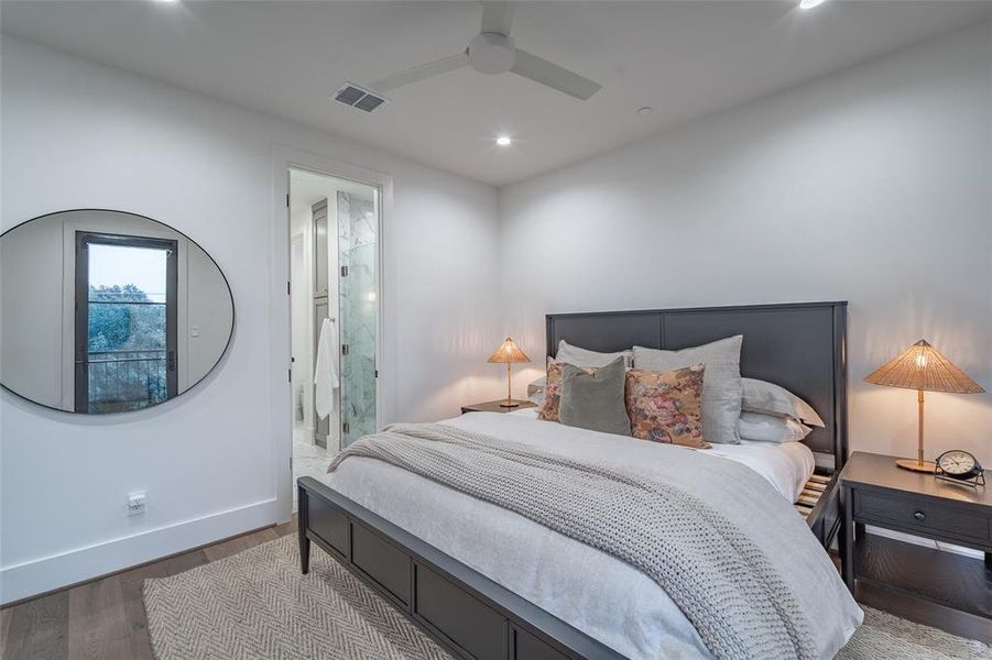 Bedroom with ensuite bathroom, ceiling fan, and light hardwood / wood-style flooring