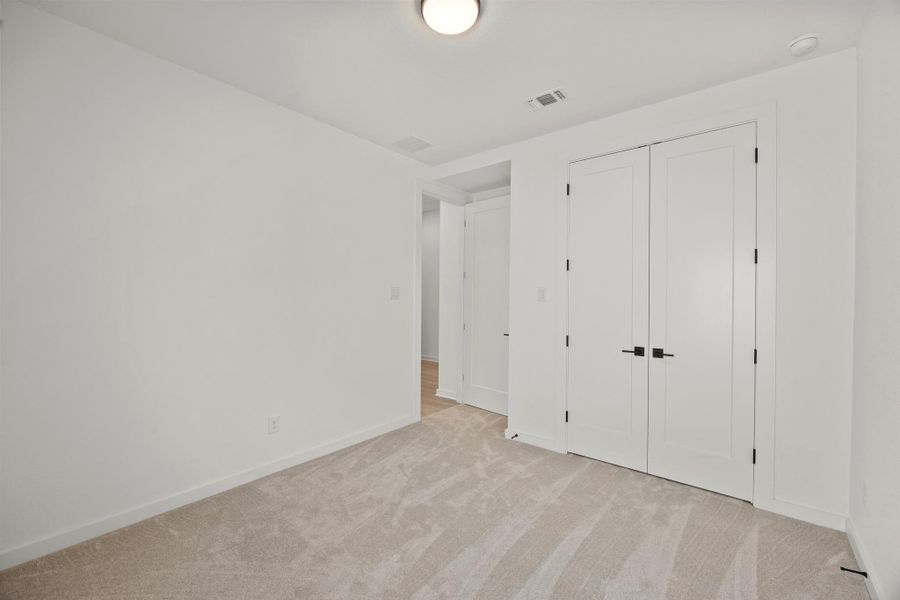 Unfurnished bedroom with light carpet and a closet