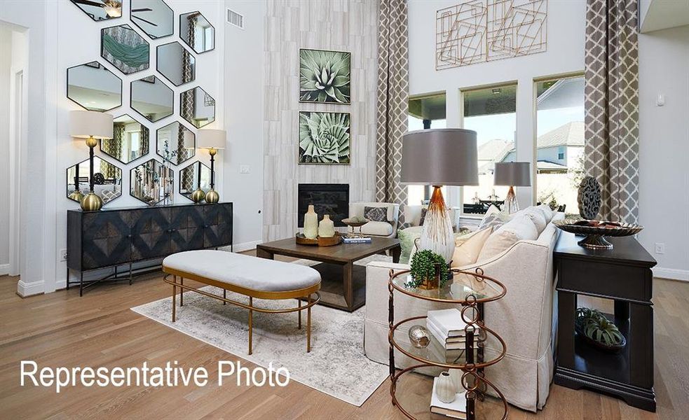 Living room featuring a high ceiling, wood-type flooring, and a tile fireplace