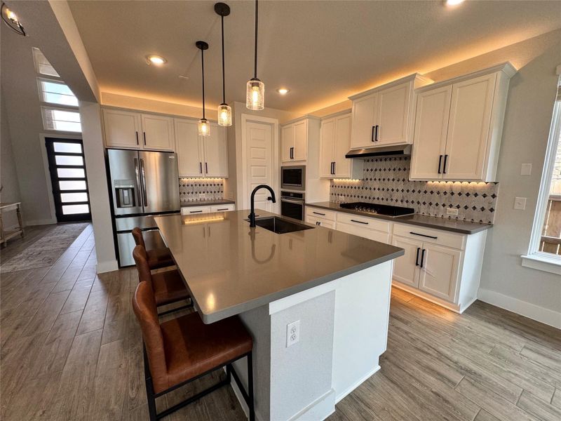Kitchen with plenty of natural light, stainless steel appliances, a kitchen bar, decorative backsplash, and recessed lighting