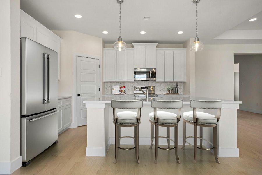 Contemporary kitchen featuring light wood-finish flooring, white cabinetry, stainless steel appliances, and a marble-patterned backsplash Contemporary kitchen featuring light wood-finish flooring, white cabinetry, stainless steel appliances, and a marble-patterned backsplash