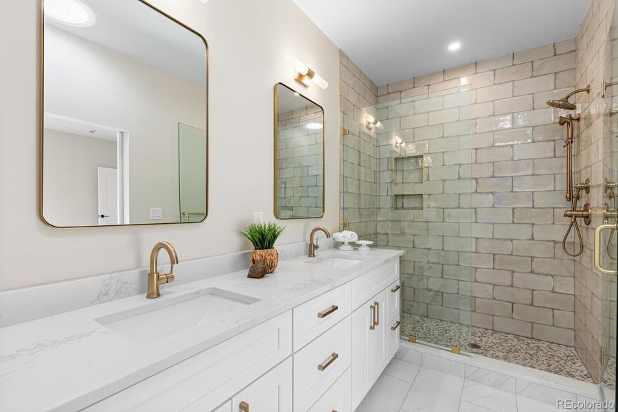 Primary bathroom with double vanities, customtile, glass enclosure, and tubular skylight Primary bathroom with double vanities, customtile, glass enclosure, and tubular skylight
