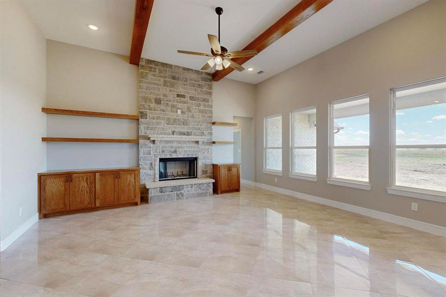 Unfurnished living room with beam ceiling, light tile patterned floors, a fireplace, and ceiling fan