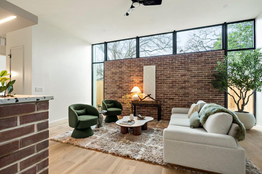 Living area featuring expansive windows, brick wall, wood finished floors, and a wealth of natural light