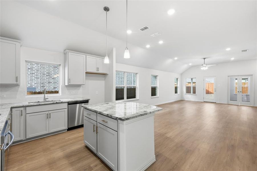 Kitchen with light wood-style floors, lofted ceiling, light stone countertops, and healthy amount of natural light Kitchen with light wood-style floors, lofted ceiling, light stone countertops, and healthy amount of natural light