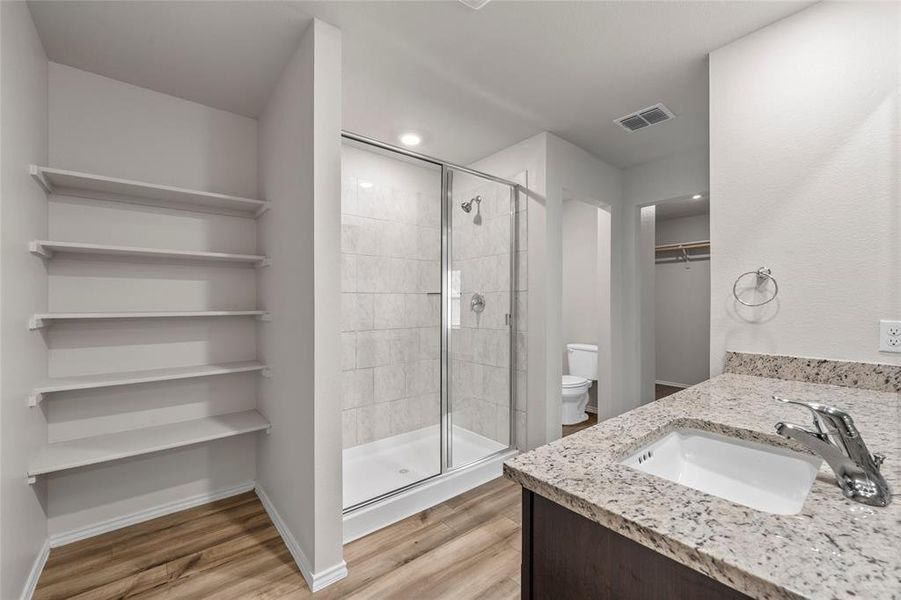 Full bath with a stall shower, wood finished floors, a walk in closet, vanity, and recessed lighting Full bath with a stall shower, wood finished floors, a walk in closet, vanity, and recessed lighting