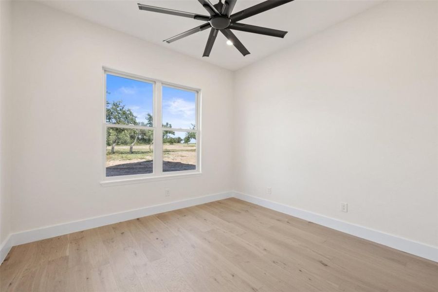 A spacious room features a wide window offering serene views of the outdoors, complemented by a modern ceiling fan. A spacious room features a wide window offering serene views of the outdoors, complemented by a modern ceiling fan.